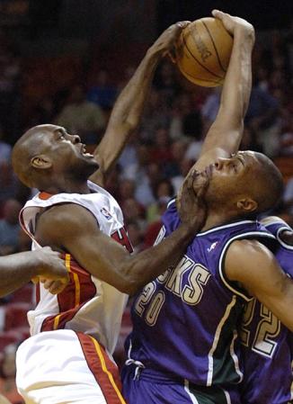 Miami Heat guard Gary Payton (L) and Milwaukee Bucks center Jamaal Magloire (R) fight for the ball during the first half of their game at the American Airlines Arena.