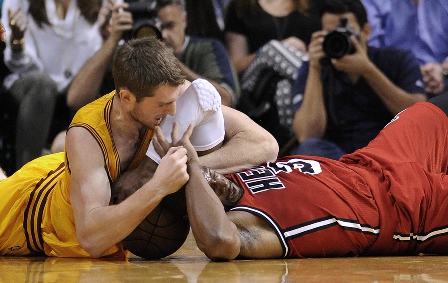 Miami Heat's Dwyane Wade (R) and Cleveland Cavaliers' Tyler Zeller (L) fight over a loose ball during the first half of their NBA basketball game in Miami, Florida, February 24, 2012.