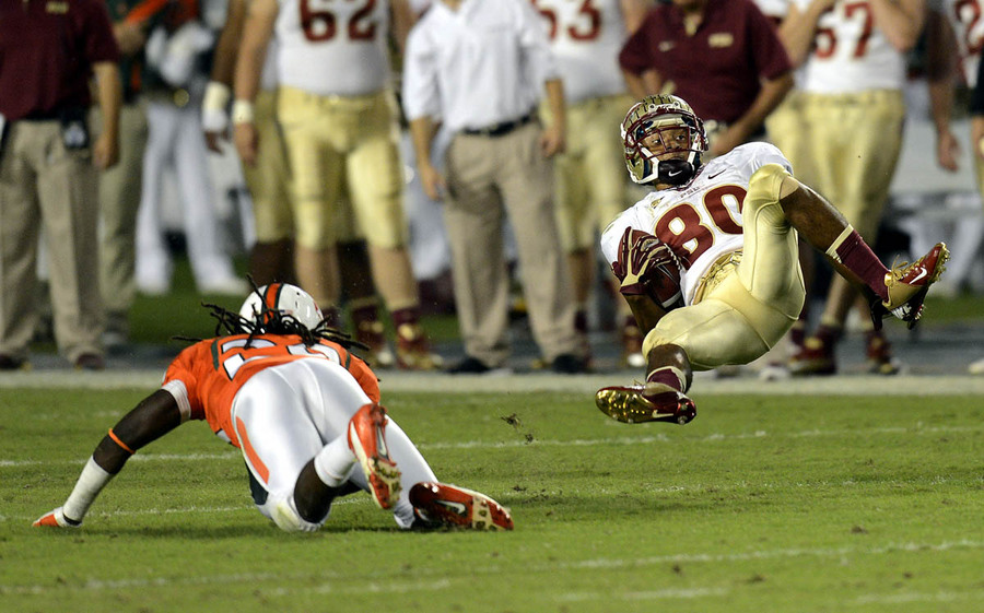 Florida State University Seminole's Rashad Greene (80) is upended by University of Miami Hurricane's Rayshawn Jenkins (29) during their NCAA football game at Sun Life Stadium in Miami, Florida