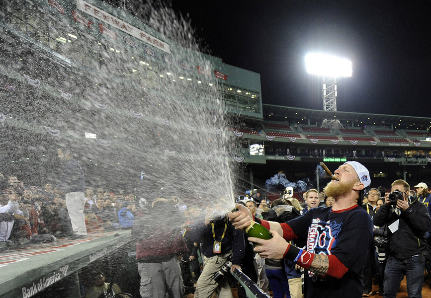 Boston Red Sox Mike Carp sprays champagne on fans after the Red Sox defeated the Detroit Tigers to win the American League Championship Series playoff game six at Fenway Park in Boston, Massachusetts
