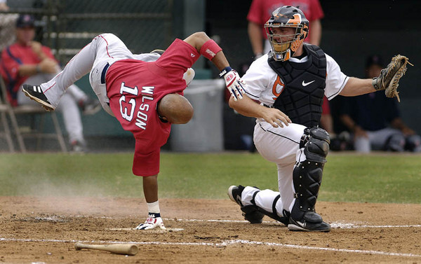 Boston Red Sox Enrique Wilson (L) is out at the plate as he is is upended by Baltimore Orioles catcher Brandon Marsters (R) during their spring training game  in Fort Lauderdale. Florida 