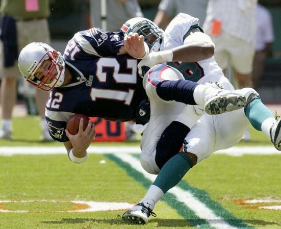 New England Patriots quarterback Tom Brady (L) is sacked by Miami Dolphins defensive tackle David Bowens (R) during first quarter action of their game  at Pro Player Stadium in Miami, Florida.