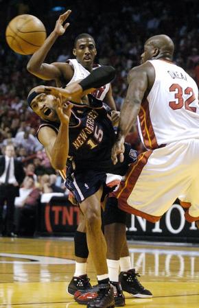 New Jersey Nets forward Vince Carter (C) loses control of the ball as he tries to pass between Miami Heat guard Eddie Jones (L) and center Shaquille O'Neal (R) during their first round playoff game two at the American Airlines Arena in Miami, Florida