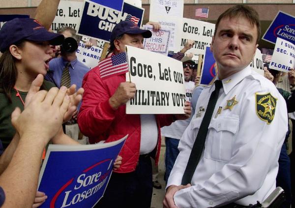 A Broward County Sheriff Chief Officer holds back a crowd of Bush-Cheney supporters as Democratic congressman Peter Duetsch tries to speak to the media 24 November 2000 at the Broward County Courthouse in Ft. Lauderdale, Florida.