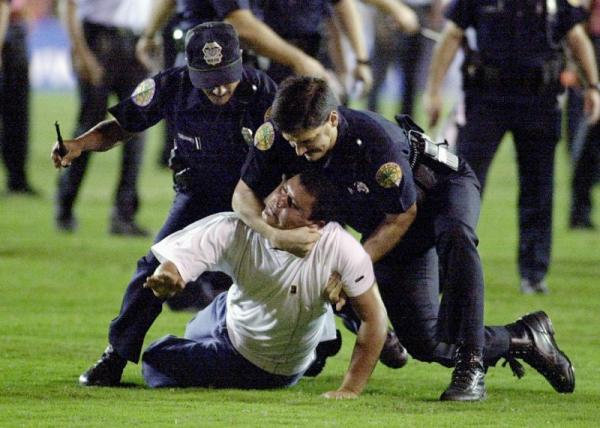 A Honduran fan is tackled by policemen in the field of the Orange Bowl after several fans jumped on the field after the main referee nullified a goal by Honduras late in the second half of their quarter-finals game in the Gold Cup at the Orange Bowl 19 February 2000 against Peru. The match was stopped with some 5 minutes remaining in the game.