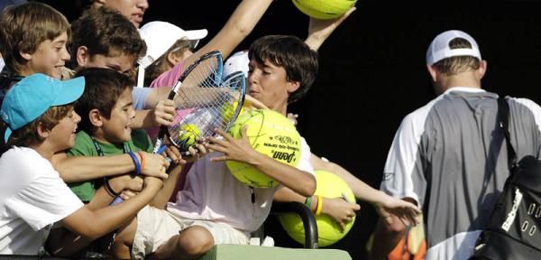 As Andy Roddick of the US exits the stadium (R) young fans fight in the stands over his broken raquet he smashed on the court during the first set of his second round match against Fernando Verdasco of Spain at the Nasdaq-100 Open in Key Biscayne, Florida.