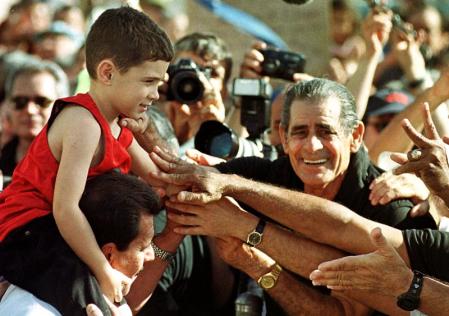 Cuban rafter Elian Gonzalez sits on his Uncle Lazaro Gonzalez's shoulders as he is greeted by a crowd of supporters outside the home of relatives 08 January, 2000, in Miami's Little Havana neighborhood. 
