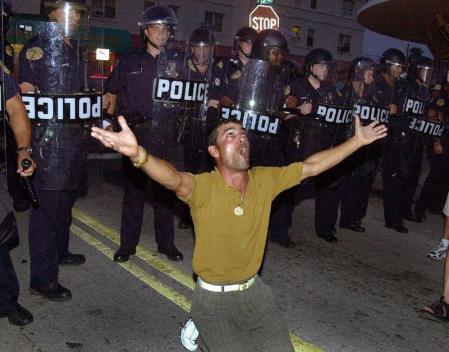 Lazaro Hernandez (C) kneels down in front of Miami city riot police close to the home of Elian Gonzalez's Miami relatives home in Miami after Federal agents stormed Gonzalez's home early 22 April 2000 and took the boy in their custody. 