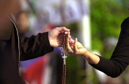 Two members of the Mothers Against Repression hold hands in prayer as they gather in front of Elian Gonzalez' Miami relative's home in Little Havana 13 April 2000. 