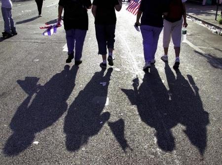 Supporters of Cuban shipwreck survivor Elian Gonzalez cast a shadow as they walk down Calle Ocho 29 April 2000 in the Little Havana section of Miami, FL. 